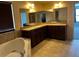 Bathroom featuring dual sinks, granite counters, tiled floors, large mirror, and a soaking tub at 12610 Sawgrass Oak St, Orlando, FL 32824