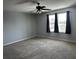 Bright bedroom with neutral carpet, two windows, and a ceiling fan at 12610 Sawgrass Oak St, Orlando, FL 32824