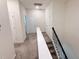 Upstairs hallway with neutral carpeting, linen closet and black metal railing at 1308 Shinnecock Hills Dr, Davenport, FL 33896