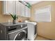 A bright laundry room features a gray washer, white dryer, and white cabinetry at 16 Sawfish Ct, Kissimmee, FL 34759
