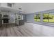 Bright kitchen and living room space featuring gray wood floors, a kitchen island, and backyard views from the large windows at 17 S Flag Ct, Kissimmee, FL 34759