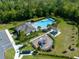 Aerial view showcasing community pool, playground, and clubhouse with ample parking surrounded by lush greenery at 17335 Million Lakes Ct, Clermont, FL 34714