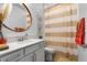 Stylish bathroom with a decorative mirror, white vanity, and a shower with a striped curtain at 17335 Million Lakes Ct, Clermont, FL 34714