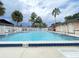 Community pool surrounded by palm trees and a white fence on a cloudy day with chair for lounging at 2316 E Margarita Ct, Kissimmee, FL 34741
