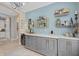 Stylish bar area featuring custom gray cabinetry, marble countertops, and a gold bottle and glass rack at 2554 Stargrass Cir, Clermont, FL 34715