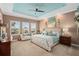 Well-lit main bedroom with a decorative tray ceiling, neutral walls, and a cozy sitting area near bright windows at 2554 Stargrass Cir, Clermont, FL 34715