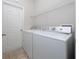 Bright laundry room with white washer, dryer, door, and wire shelf, enhancing home convenience at 313 Greenwich Ct, Kissimmee, FL 34758
