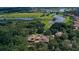 Aerial view of estate home with custom roof surrounded by dense trees, golf course, and ponds at 31754 Red Tail Blvd, Sorrento, FL 32776