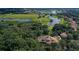 Aerial view of estate home with custom roof surrounded by dense trees, golf course, and ponds at 31754 Red Tail Blvd, Sorrento, FL 32776
