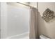 Clean, tiled tub and shower combination with neutral beige walls and decorative wall decor at 31754 Red Tail Blvd, Sorrento, FL 32776