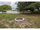 Backyard with a circular stone fire pit surrounded by grass, trees, and a white fence at 3300 Needles Dr, Orlando, FL 32810