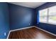 A dark blue empty room has a shiny wood floor, bright window, and blue nebula curtain at 3300 Needles Dr, Orlando, FL 32810
