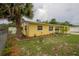 Quaint yellow home showcasing vibrant landscaping, a well-maintained lawn, and a decorative palm tree at 3300 Needles Dr, Orlando, FL 32810