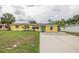 Charming one-story yellow home featuring a lush lawn, colorful landscaping, and a long driveway at 3300 Needles Dr, Orlando, FL 32810