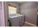 Convenient laundry room with washer, dryer, overhead storage, and tiled floors at 3300 Needles Dr, Orlando, FL 32810