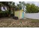 Backyard shed with a light blue door surrounded by trees, grass, and a white fence at 3300 Needles Dr, Orlando, FL 32810