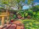 Secluded backyard featuring a garden with brick path, mature trees, and lush green grass at 420 S Oak Ave, Sanford, FL 32771