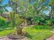 Secluded backyard showcasing a garden with manicured lawn, flower beds, and mature trees at 420 S Oak Ave, Sanford, FL 32771