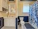 Well-lit bathroom with white cabinetry, patterned tile floor, and a shower with a floral curtain at 420 S Oak Ave, Sanford, FL 32771