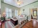 Comfortable bedroom with hardwood floors, white metal bed frame, and a decorative ceiling fan at 420 S Oak Ave, Sanford, FL 32771