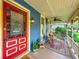 Inviting front porch with a red door, ceiling fan, and wicker rocking chairs at 420 S Oak Ave, Sanford, FL 32771