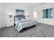 Cozy bedroom with gray carpet, a queen bed with blue accents, and matching blue lamps on the white bedside tables at 6328 Whip O Will Ln, St Cloud, FL 34771