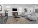 Bright living room featuring a gray sofa, two chairs, a wooden cabinet and a modern coffee table at 6328 Whip O Will Ln, St Cloud, FL 34771