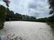 Outdoor sand volleyball court with professional net set amid mature landscaping and cloudy sky at 639 Longboat Dr, Davenport, FL 33896