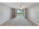 The bright living room features neutral paint, carpet, ceiling fan, and sliding glass doors to the balcony at 7511 Seurat St # 10207, Orlando, FL 32819