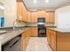 Well-lit kitchen featuring wooden cabinetry, granite countertops, and modern black appliances at 7513 Brightwater Pl, Oviedo, FL 32765
