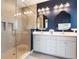 Bright bathroom featuring a double sink vanity, framed mirrors, and glass shower stall at 8478 Karrer Ter, Orlando, FL 32827