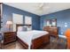 Comfortable blue bedroom with a wooden bed frame, dark floors, and plenty of natural light at 8478 Karrer Ter, Orlando, FL 32827