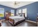 Comfortable blue bedroom with a ceiling fan, wood floors, and plenty of natural light at 8478 Karrer Ter, Orlando, FL 32827