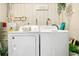Bright laundry room featuring a washer, dryer, utility sink and modern wallpaper at 10148 Eventide Ct, Orlando, FL 32821