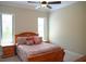 Cozy bedroom with a wooden bed frame, soft bedding, neutral walls, and natural light from two windows at 11013 Ullswater Ln, Windermere, FL 34786