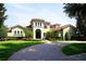Stunning Mediterranean-style home with lush landscaping, tile roof, and a circular brick driveway leading to the grand entrance at 11013 Ullswater Ln, Windermere, FL 34786