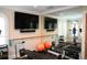 Bright home gym features a mirrored wall with mounted TVs for an immersive workout at 11013 Ullswater Ln, Windermere, FL 34786