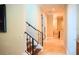Hallway with travertine floors leads to a bathroom and features stairs with dark wrought iron railing at 11013 Ullswater Ln, Windermere, FL 34786