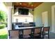 An outdoor kitchen includes a gas grill, bar seating and countertop, along with a wall-mounted television at 11013 Ullswater Ln, Windermere, FL 34786