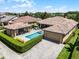 Aerial view showcasing a backyard pool and spa, surrounded by lush landscaping and multiple buildings at 11755 Waterstone Loop Dr, Windermere, FL 34786