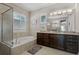 Bathroom showcasing a standalone tub, granite counters, dark cabinetry, and plantation shutters at 11755 Waterstone Loop Dr, Windermere, FL 34786