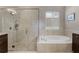 Bathroom view of the soaking tub and shower with pebble floor, paired with brown cabinets at 11755 Waterstone Loop Dr, Windermere, FL 34786