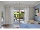 Bedroom view to the bricked patio and pool through sliding glass doors draped with sheer white curtains at 11755 Waterstone Loop Dr, Windermere, FL 34786