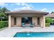 Poolside seating area with tiled roof cabana offers a tranquil spot to unwind and enjoy the peaceful water views at 11755 Waterstone Loop Dr, Windermere, FL 34786