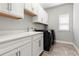 Modern laundry room with white cabinets, gray walls, and black washer and dryer at 1272 Patterson Ter, Lake Mary, FL 32746