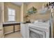 Well-organized laundry room with modern washer, dryer, storage shelves, and counter space at 1356 Coralstone Dr, Celebration, FL 34747