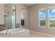 Well-lit main bathroom features a large soaking tub, glass shower, and multiple windows at 13661 Granger Ave, Orlando, FL 32827