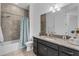 Well-lit bathroom with granite countertops, tiled shower with blue patterned curtain, and a decorative mirror at 14072 Alafaya Oak Bnd, Orlando, FL 32828
