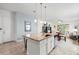 Modern kitchen island with a granite countertop, stainless steel sink, and seating, open to dining and living spaces at 14072 Alafaya Oak Bnd, Orlando, FL 32828