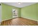 This is a view of an empty bedroom, with light green walls and wood-look flooring and a window view to the neighborhood at 150 Tarpon Cir, Winter Springs, FL 32708